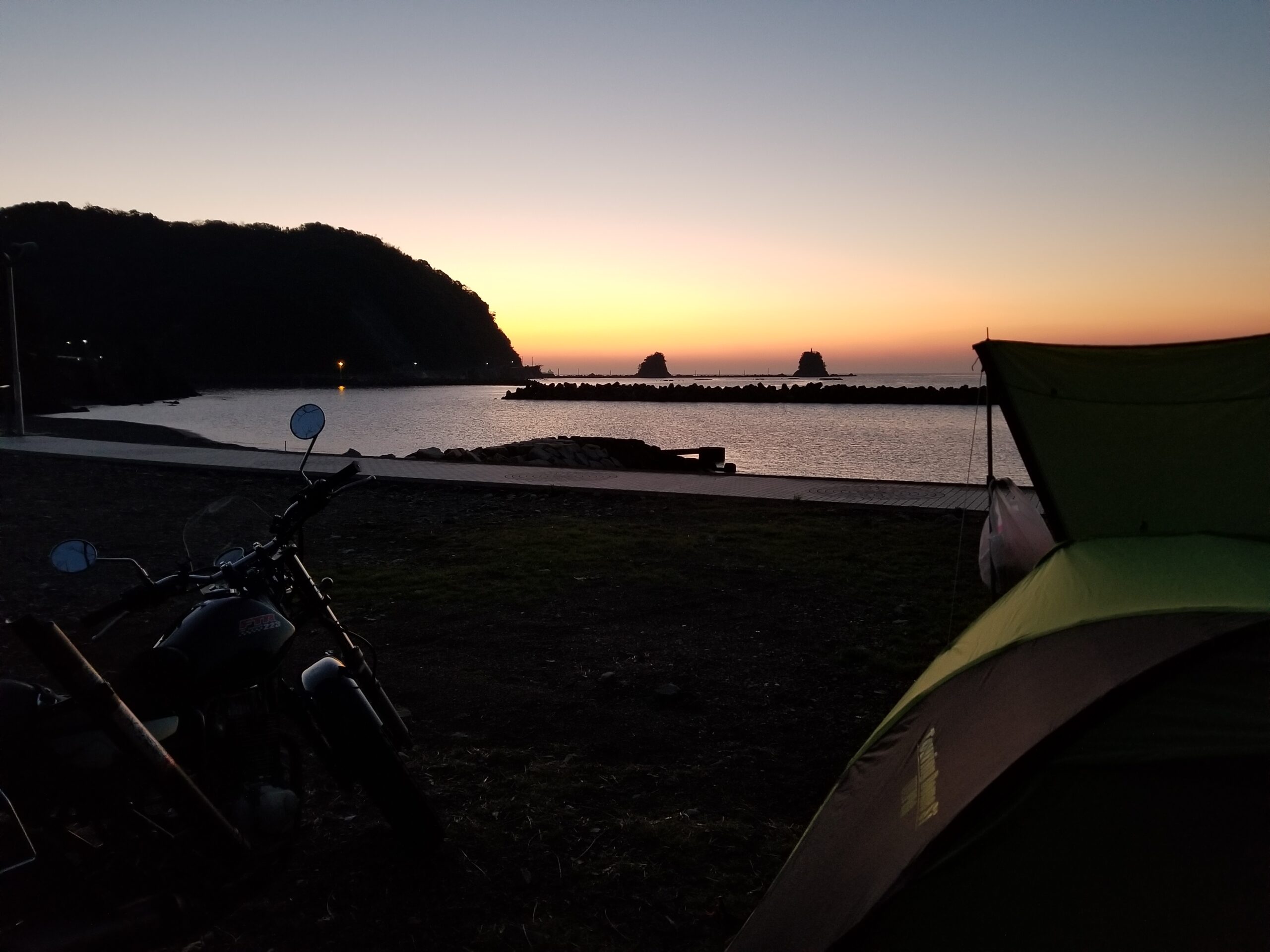 海辺で日の出を待つバイクとテント